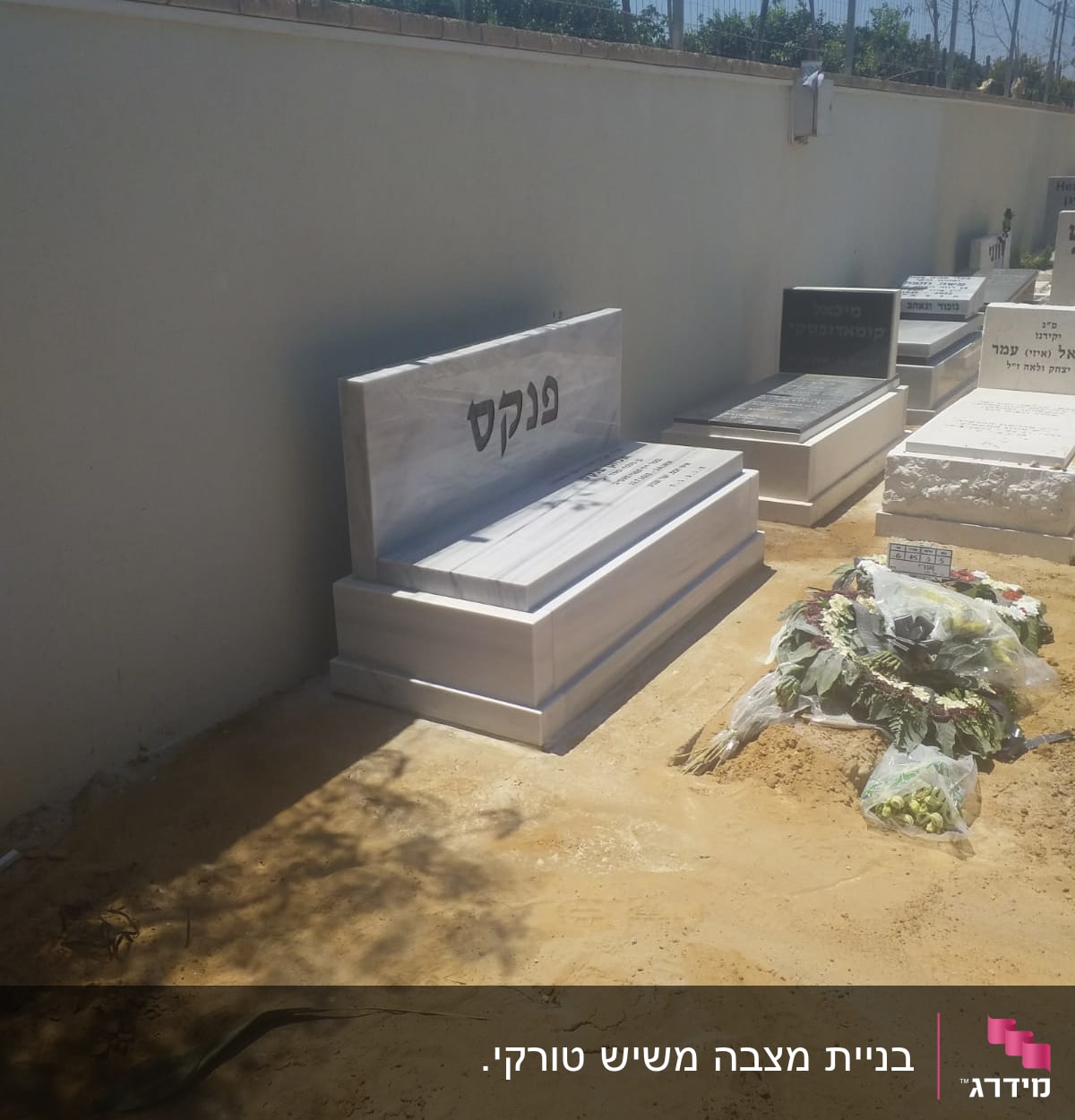 מצבות בבית קברות עם כיתוב בעברית וזרי פרחים